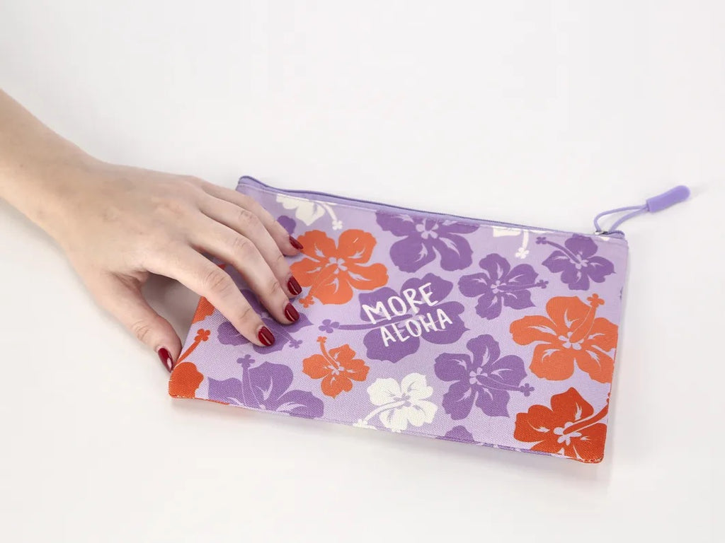 Purple pouch with floral designs and 'More Aloha' text held by a hand on a white background