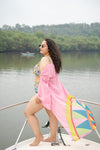 Woman in a colorful bikini and pink cover-up on a boat with a scenic background