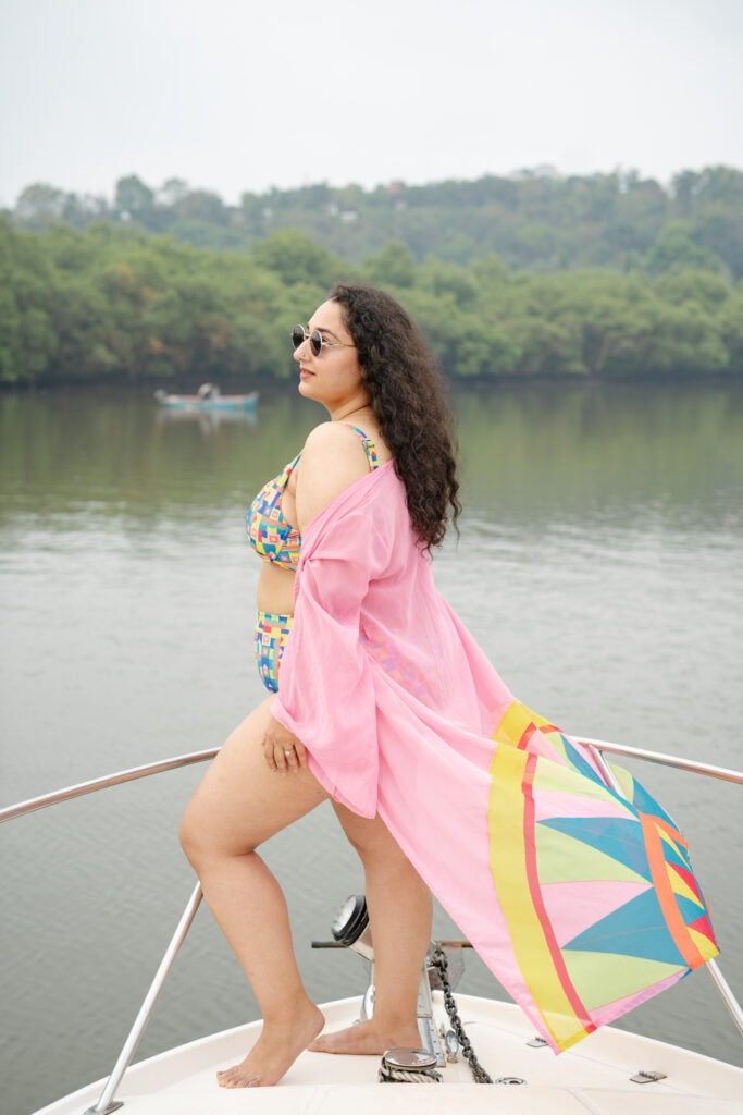 Woman in a colorful bikini and pink cover-up on a boat with a scenic background