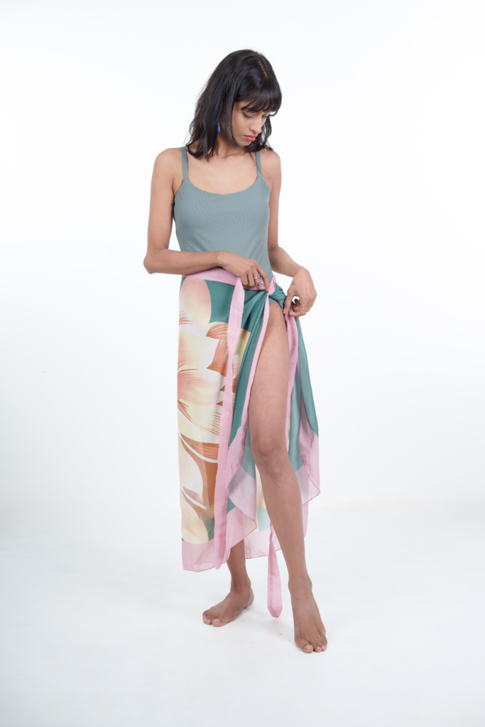 Woman wearing a light blue tank top and a colorful floral skirt on a white background