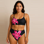 Woman wearing a black bikini with pink floral designs against a beige background